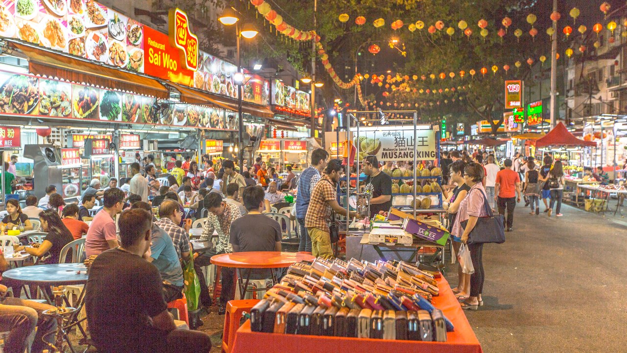 A bustling Kuala Lumpur hawker street lit up at night