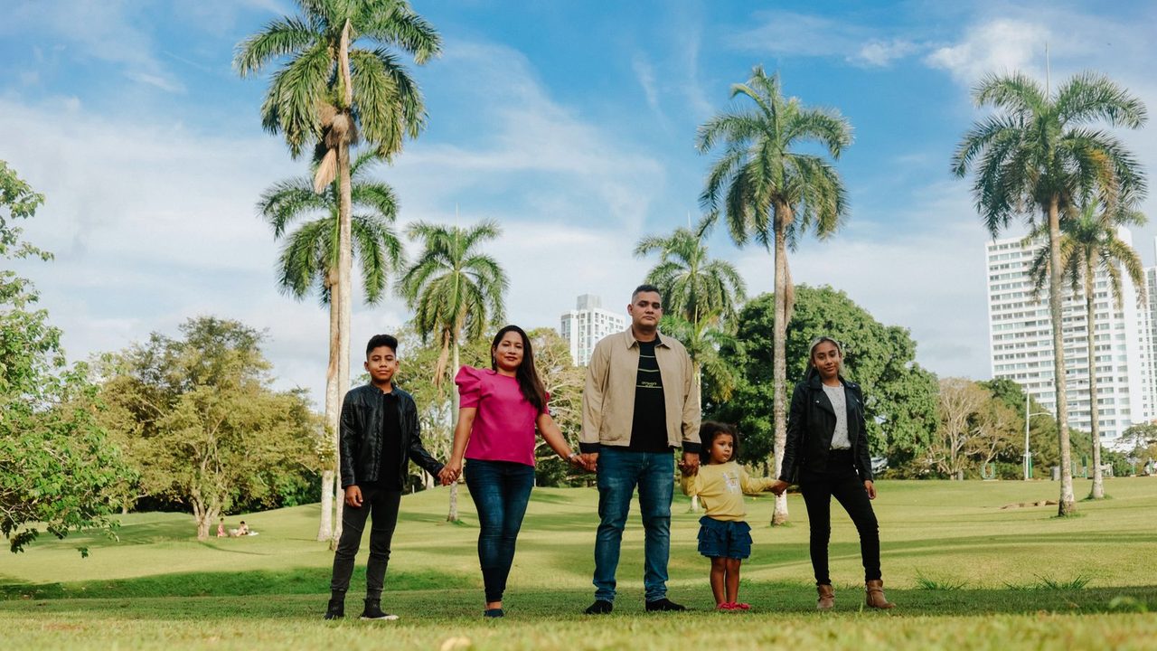 A family in a green, tree-lined city park